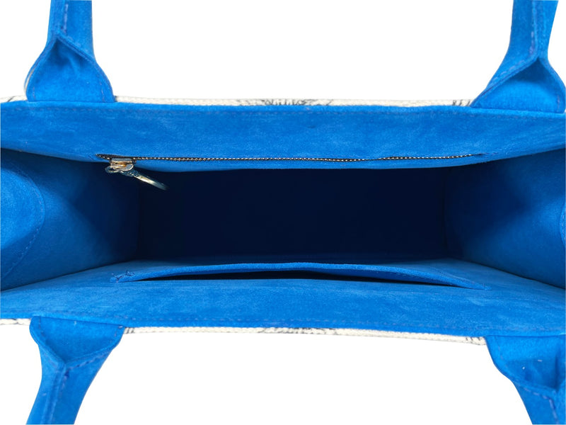 Showing the inside of the tote bag interior in blue suede with 2 inside pockets, 1 is zippered