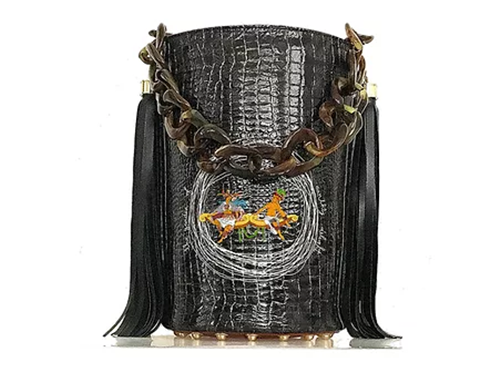 Black glossy croc effect printed leather bucket handbag with two colorful indigenous people sitting on a bench having a quiet conversation . Chain resin handle and leather tassels on each side of the bag
